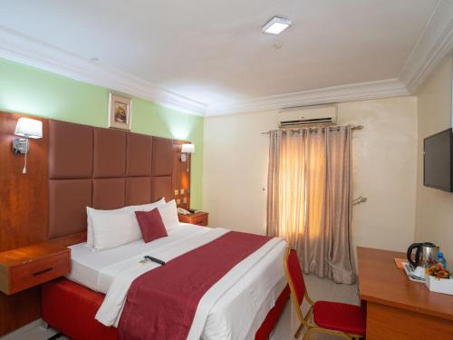a hotel room with a bed and a desk and a television at Charriot Hotels in Abuja
