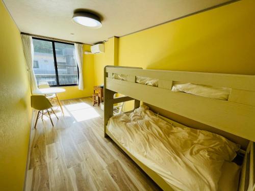 a bedroom with a bunk bed and a yellow wall at Cafe&Stay Stella in Minakami