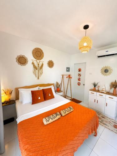 a bedroom with a bed with an orange blanket at MCRentals Siquijor in San Juan