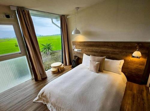 a bedroom with a large bed and a large window at 好和院景田旅 How Has in Chishang