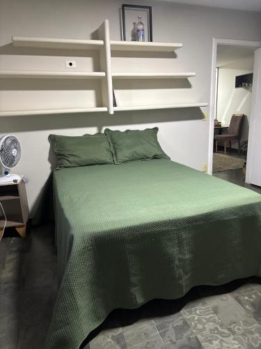 a bedroom with a bed with green sheets and shelves at Rondon Sunset Belas Artes - 3Q - 3 salas - Sacada in Uberlândia