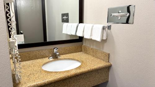 a bathroom with a sink and a mirror and towels at Days Inn by Wyndham Rio Rancho in Rio Rancho