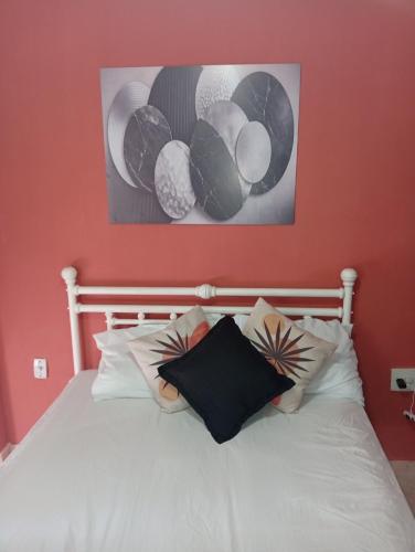 a bed with white sheets and pillows under a painting at Studio Royal Trianon Centro in Campos dos Goytacazes