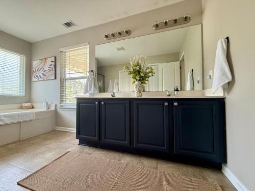 a bathroom with a black vanity with a large mirror at Fenced Yard, Pool, Lazy River SAV Area Oasis! in Savannah