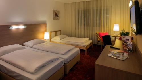 um quarto de hotel com duas camas e uma secretária em Kaiserrast em Stockerau