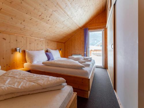 two beds in a room with wooden walls and a window at Tauern Lodge in Hohentauern