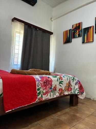 a bedroom with a bed with a red blanket and a window at Buganvilias Quepos No 1 con aire acondicionado in Quepos