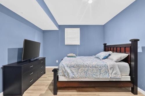 a bedroom with blue walls and a bed with a television at Sunshine Cozy Crib in Glenarden