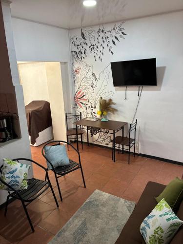 a living room with a table and chairs and a tv at Buganvilla Quepos No 2 Aire acondicionado in Quepos