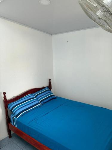 a bed with blue sheets in a white room at Buganvilla No 3 Aire Acondicionado in Quepos