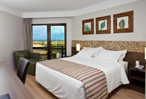 a hotel room with a large bed and a window at Celi Hotel Aracaju in Aracaju