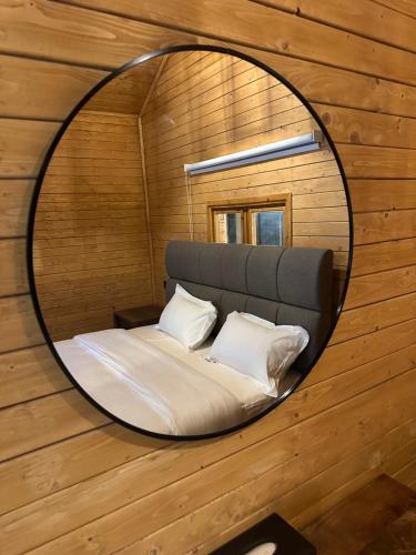 a circular mirror reflecting a bed in a room at اكواخ سمر in Abha