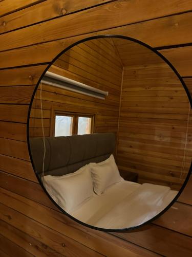 a mirror on a wall with a bed in a room at اكواخ سمر in Abha