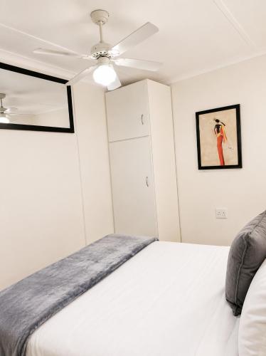 a bedroom with a white bed and a ceiling fan at Tiah Grey, Durban in Durban