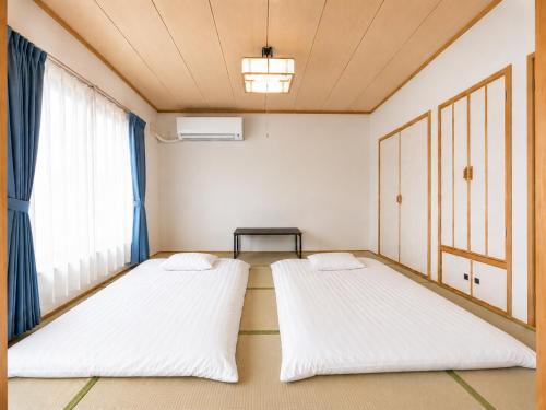 two beds in a room with a window at Moio Homestay in Sapporo