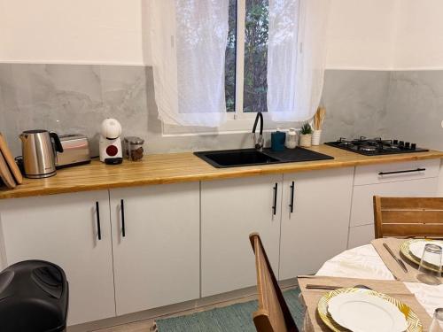 a kitchen with white cabinets and a sink and a table at Sunshine Privilège in Deshaies