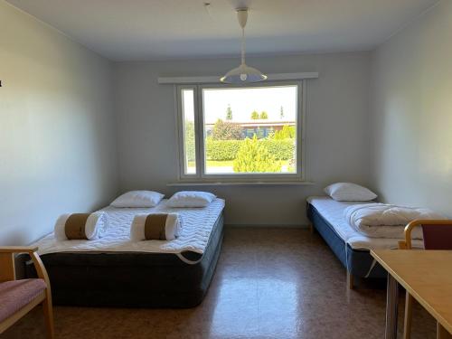 two beds in a room with a window at Private apartment in Kokkola