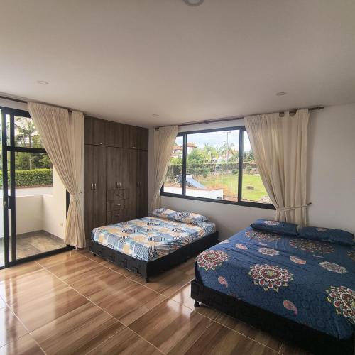a bedroom with two beds and a large window at Villa Conejo Miraflores in Chinauta