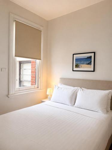 a white bed in a bedroom with a window at Pier Hotel Port Lincoln in Port Lincoln