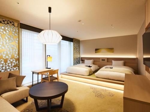 a bedroom with two beds and a couch and a table at Hotel Intergate Hiroshima in Hiroshima