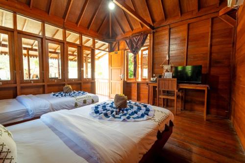 a bedroom with two beds and a desk with a television at Welly Bungalow in Gili Trawangan