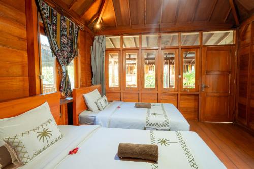 two beds in a room with wooden walls at Westwood Bungalow in Gili Trawangan