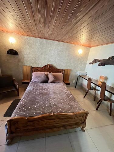 a bedroom with a wooden bed with a wooden ceiling at Pousada Vertente das Águas in Lumiar