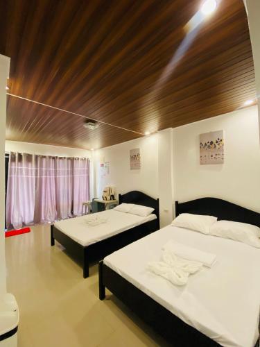 two beds sitting in a room with at Strangers Inn&Bar in General Luna