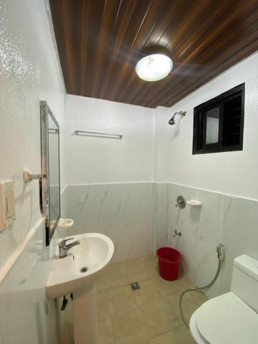 a white bathroom with a sink and a toilet at Strangers Inn&Bar in General Luna