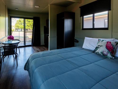 a bedroom with a large blue bed and a table at Longreach Tourist Park in Longreach