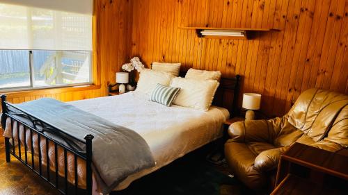 a bedroom with a bed and a leather chair at Marlo Tide Retreat in Marlo