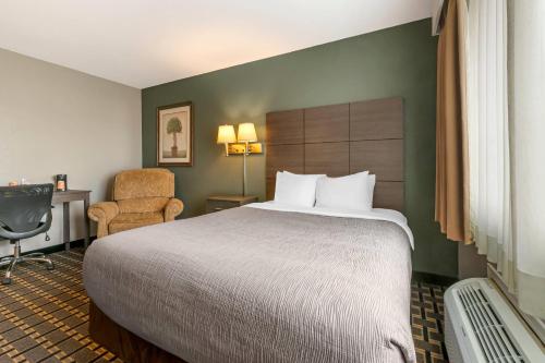 a hotel room with a large bed and a chair at Quality Inn Mauston I-90 in Mauston