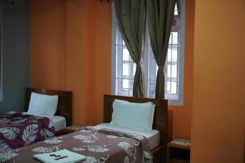a room with two beds and a window at Monshing Homestay - Elevate your travel experience in Bomdila
