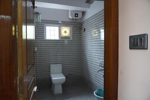 a bathroom with a white toilet and a window at Monshing Homestay - Elevate your travel experience in Bomdila