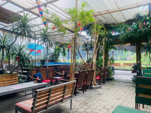 a patio with tables and chairs and palm trees at Big J Hostel in Ninh Binh