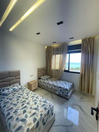 a bedroom with two beds and a large window at Appartement direct aan zee in Azla-Tetouan in Azla