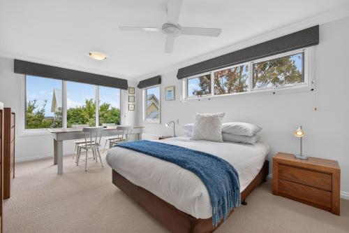 a bedroom with a bed and a table and windows at Foreshore - Spacious Metung Escape in Metung