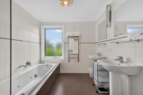 a white bathroom with two sinks and a bath tub at Foreshore - Spacious Metung Escape in Metung