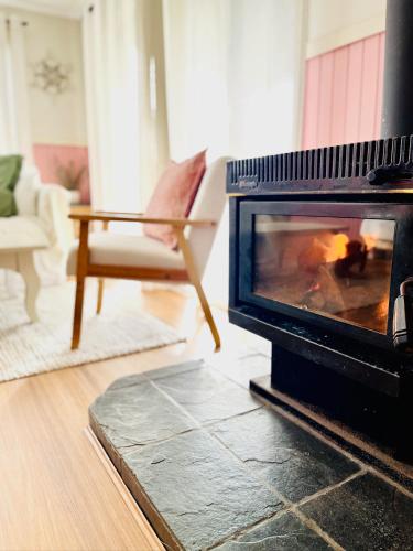 a living room with a fireplace and a chair at Shell Shack in Tomakin
