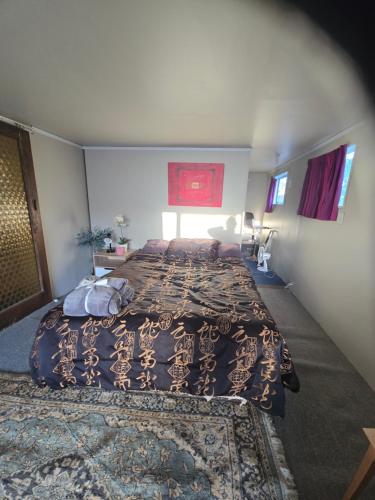 a bedroom with a large bed and a rug at Affordable pit stop Te Horo Beach in Te Horo