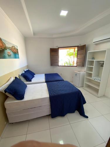 a bedroom with a bed with blue sheets and a window at Hotel Mandacaru in Piranhas