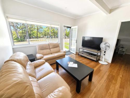 a living room with a couch and a table at Harbour Breeze - apartment in Ulladulla in Ulladulla