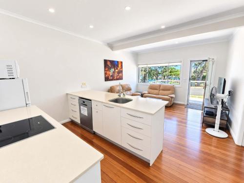 a kitchen with a sink and a living room at Harbour Breeze - apartment in Ulladulla in Ulladulla