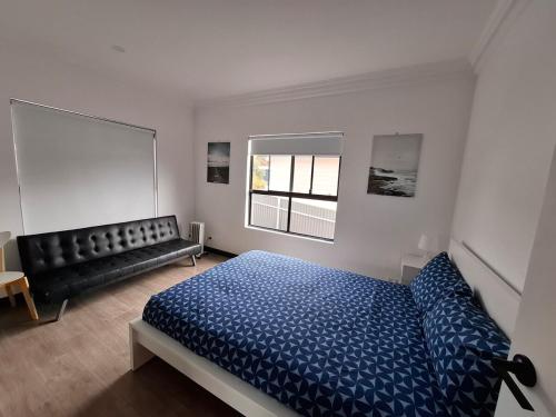 a bedroom with a blue bed and a black couch at Stunning sea views & golf course in Penneshaw