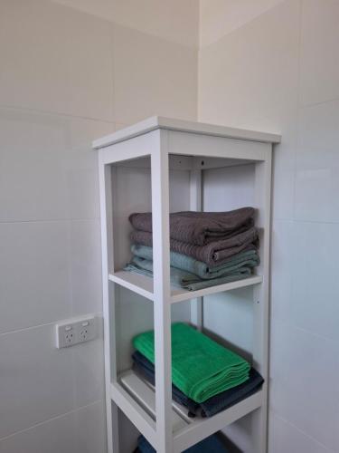 a white shelf with towels on it in a bathroom at Stunning sea views & golf course in Penneshaw
