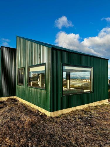 a green building with two windows in a field at Cabaña Julián Elias Verde in Puerto Natales