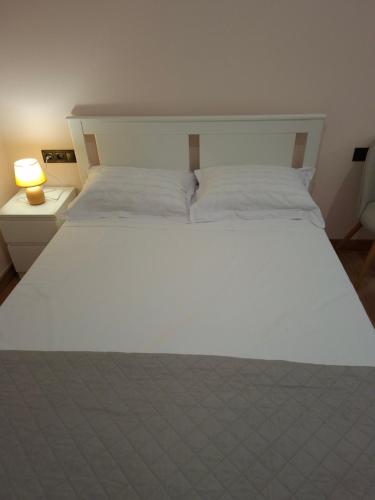 a large white bed in a room with a lamp at Mare e Vita in Patitiri