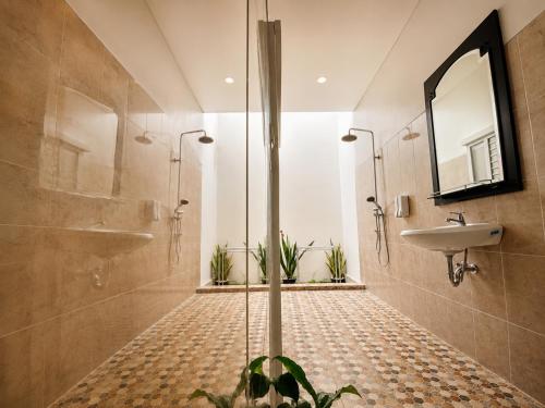 a bathroom with a shower and a sink and a mirror at Pondok DlodPoh in Karangasem