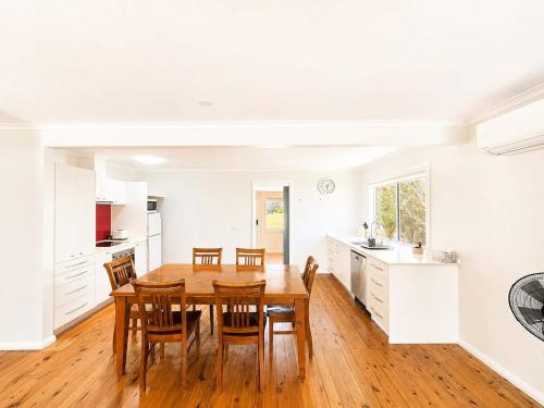 a kitchen and dining room with a wooden table and chairs at Harbour Haven - steps from Ulladulla Harbour in Ulladulla