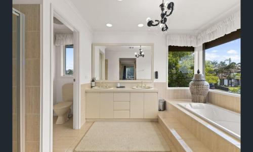 a bathroom with a tub and a sink and a tub and a mirror at Sarovar Holidays in Traralgon